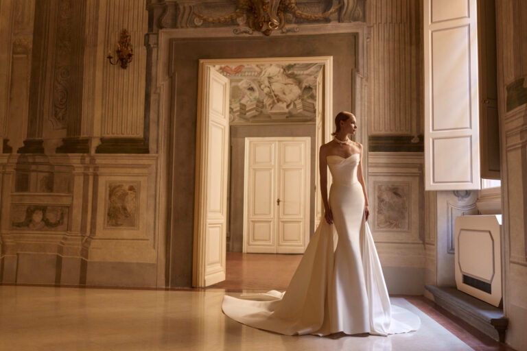 Elanith by Milla Nova Fitted sheath mikado plain wedding dress with detailed bodice and cap sleeves for the bardot off the shoulder look. With optional removal overskirt train extention