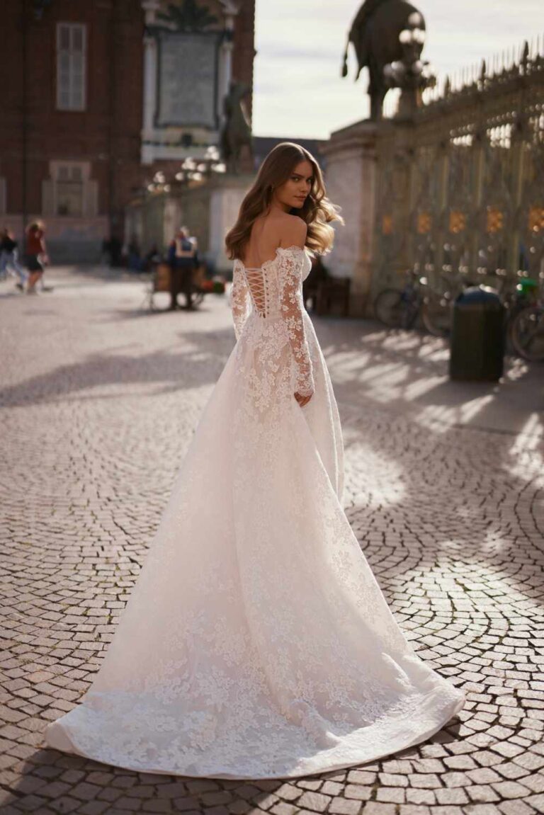 Lotta by ivory bridal is a delicate lace alim wedding dress with corset bodice and long sleeves set in an Italian courtyard at Wedding Belles of Four Oaks
