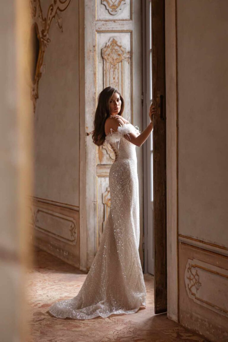 Raquel wedding dress at wedding Belles of Four Oaks is a glamorous beaded off the shoulder wedding Belles with detachable feather detail